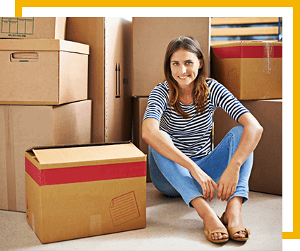 Smiling student sitting by a stack of moving boxes